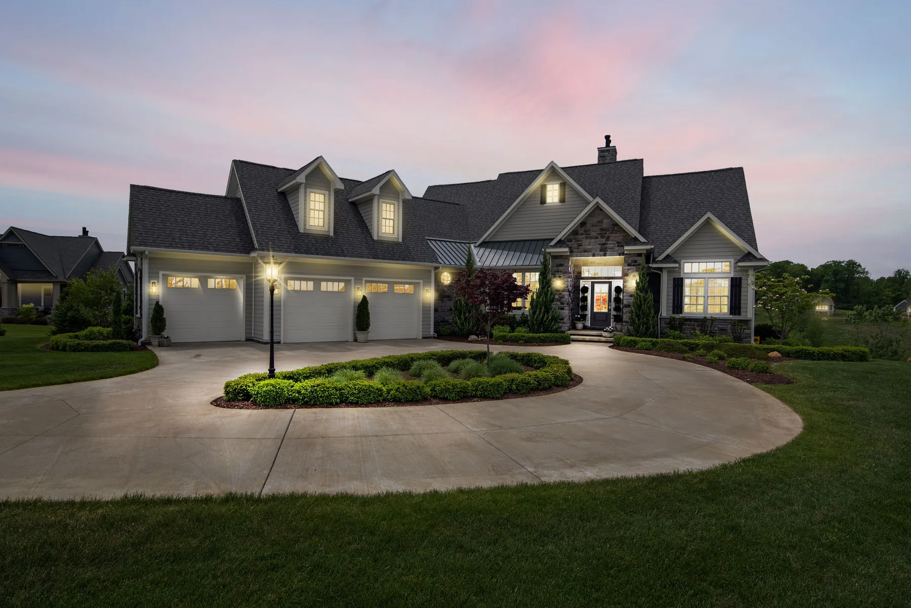 A Lowcountry home at dusk with landscape lighting washing the façade and a freshly irrigated lawn