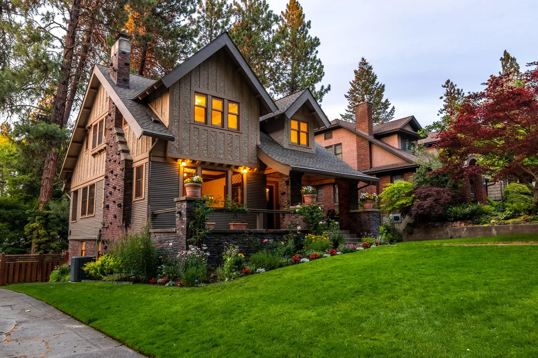 A home façade and front landscaping washed with warm low-voltage lighting at dusk